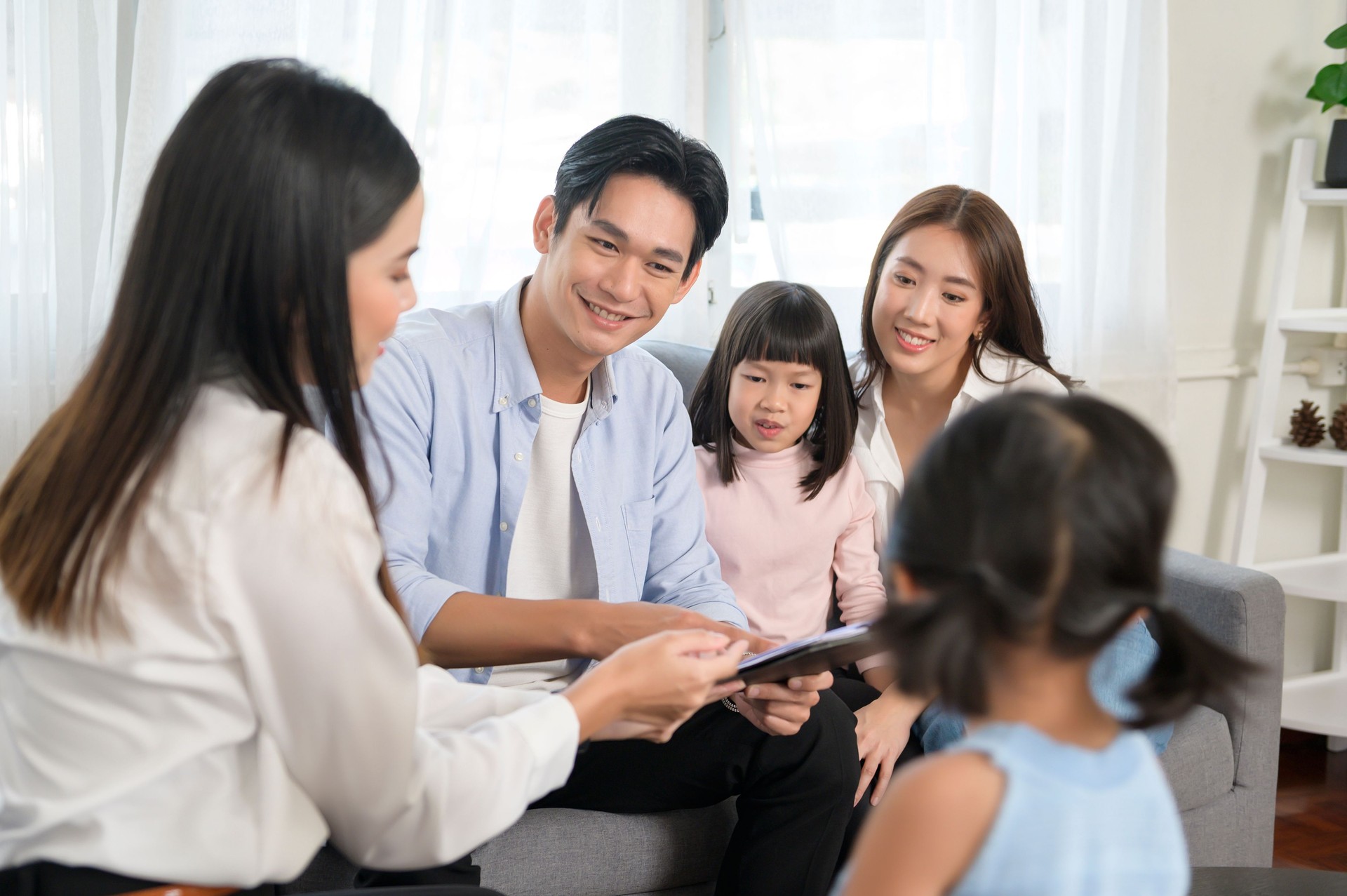 Asian family meeting with female real estate agent or insurance consultant offering promotions , Mortgage, loan, property and medical health insurance concept.