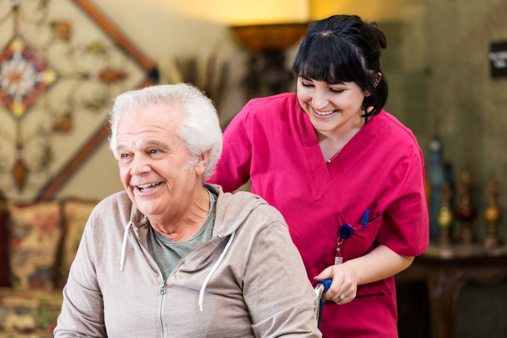 Nursing technician pushes senior man in wheelchair