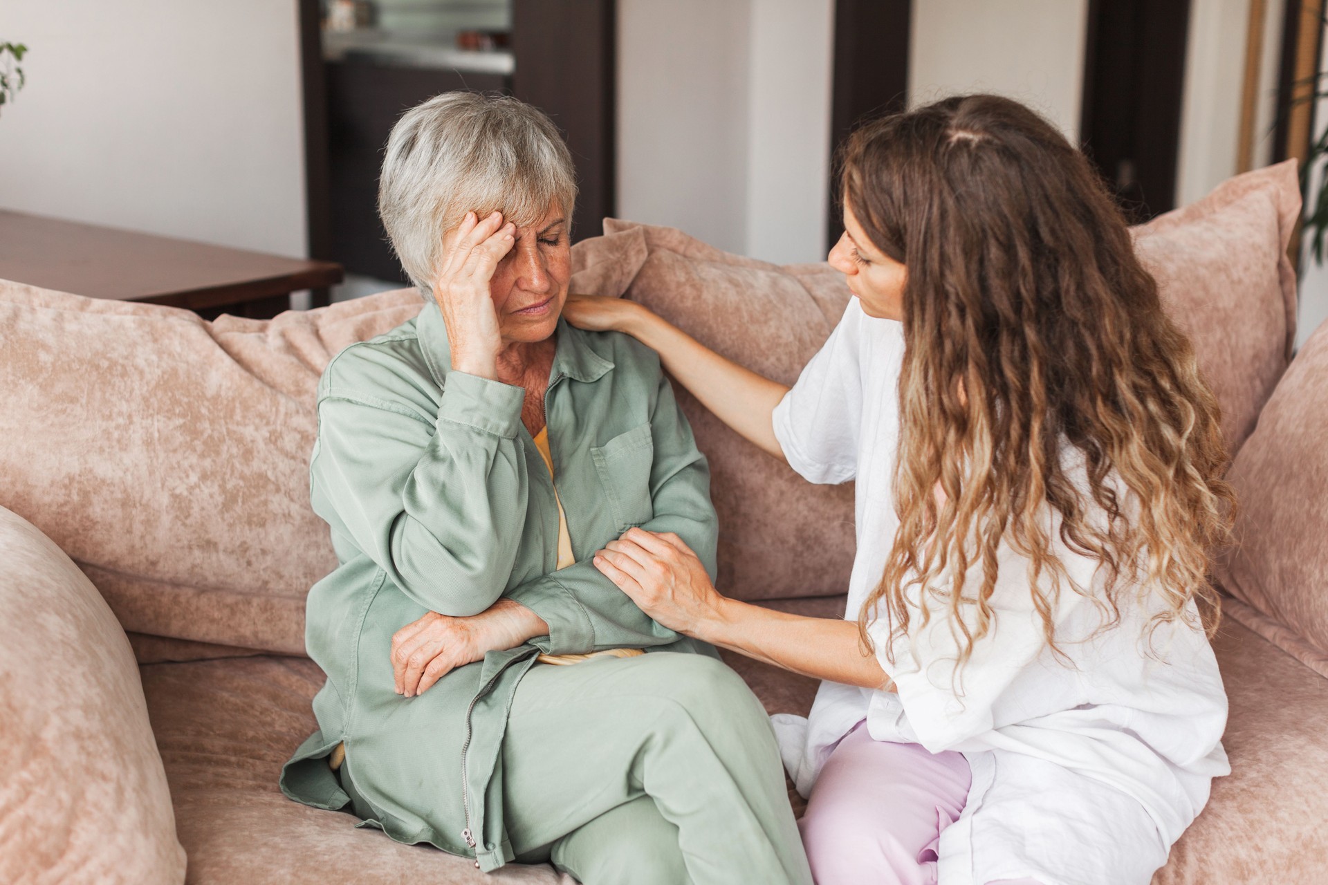 Grown up daughter soothe aged mother holds her hand feel empathy give her moral support, sad elderly woman at home